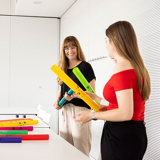 Lehrerin und Schülerinnen nutzen in der Gruppe Plastikrohre zum Musik machen